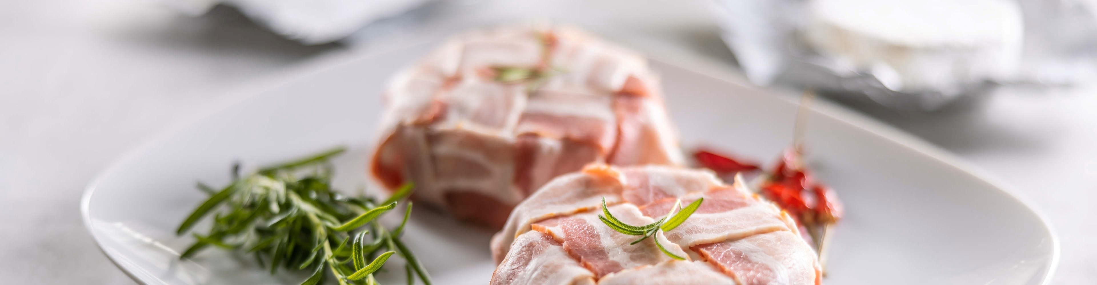 Roți de brânză Camembert învelite în bacon și decorate cu rozmarin, pregătite pentru a fi gătite la grătar