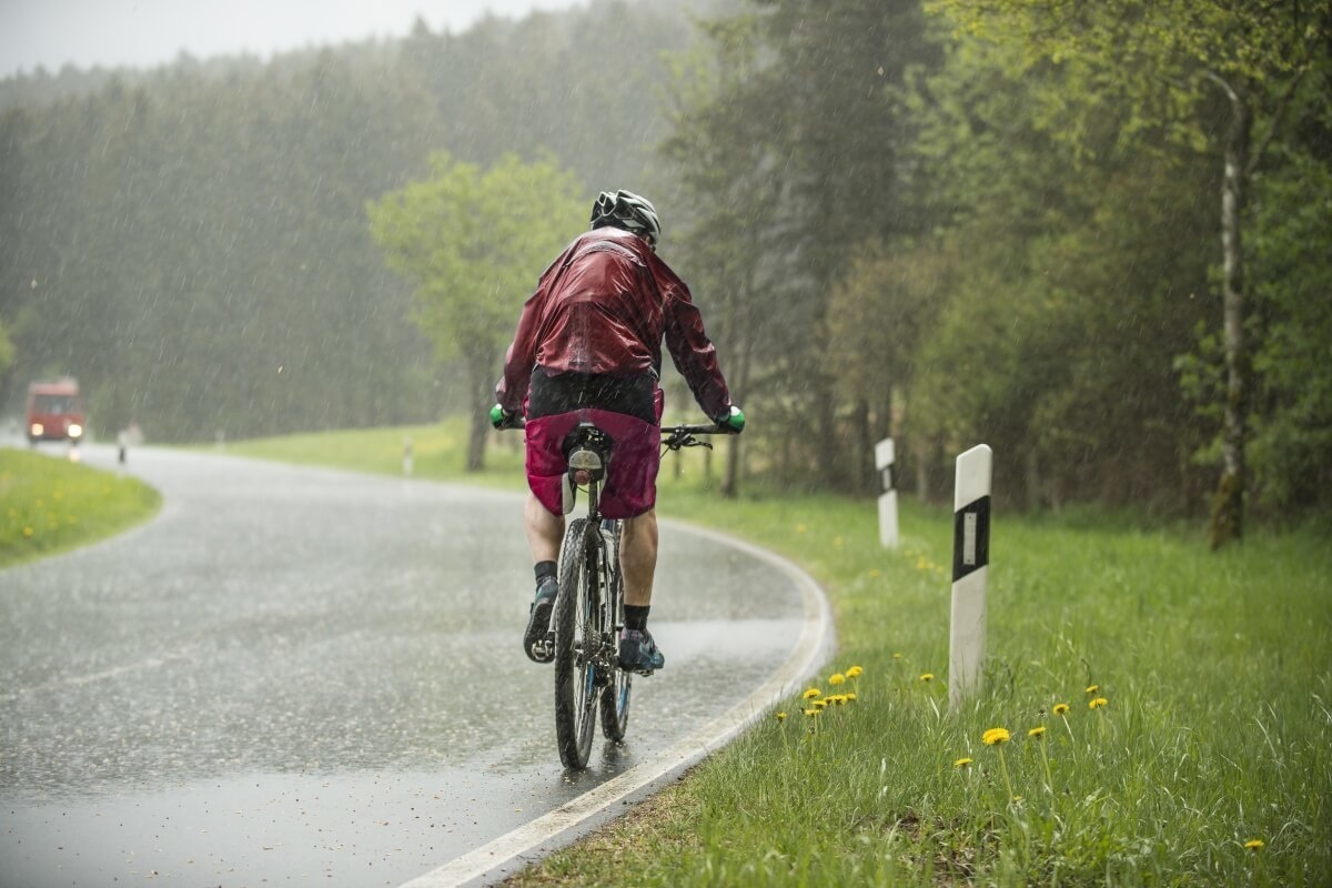 Ciclist echipat corespunzător pedalând prin ploaie Ce se poate întâmpla într-o excursie cu bicicleta