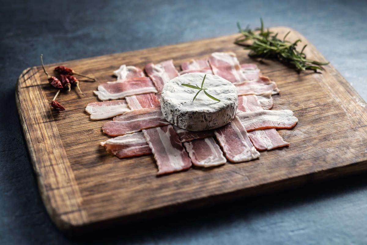 Brânză Camembert așezată pe o împletitură din felii de bacon