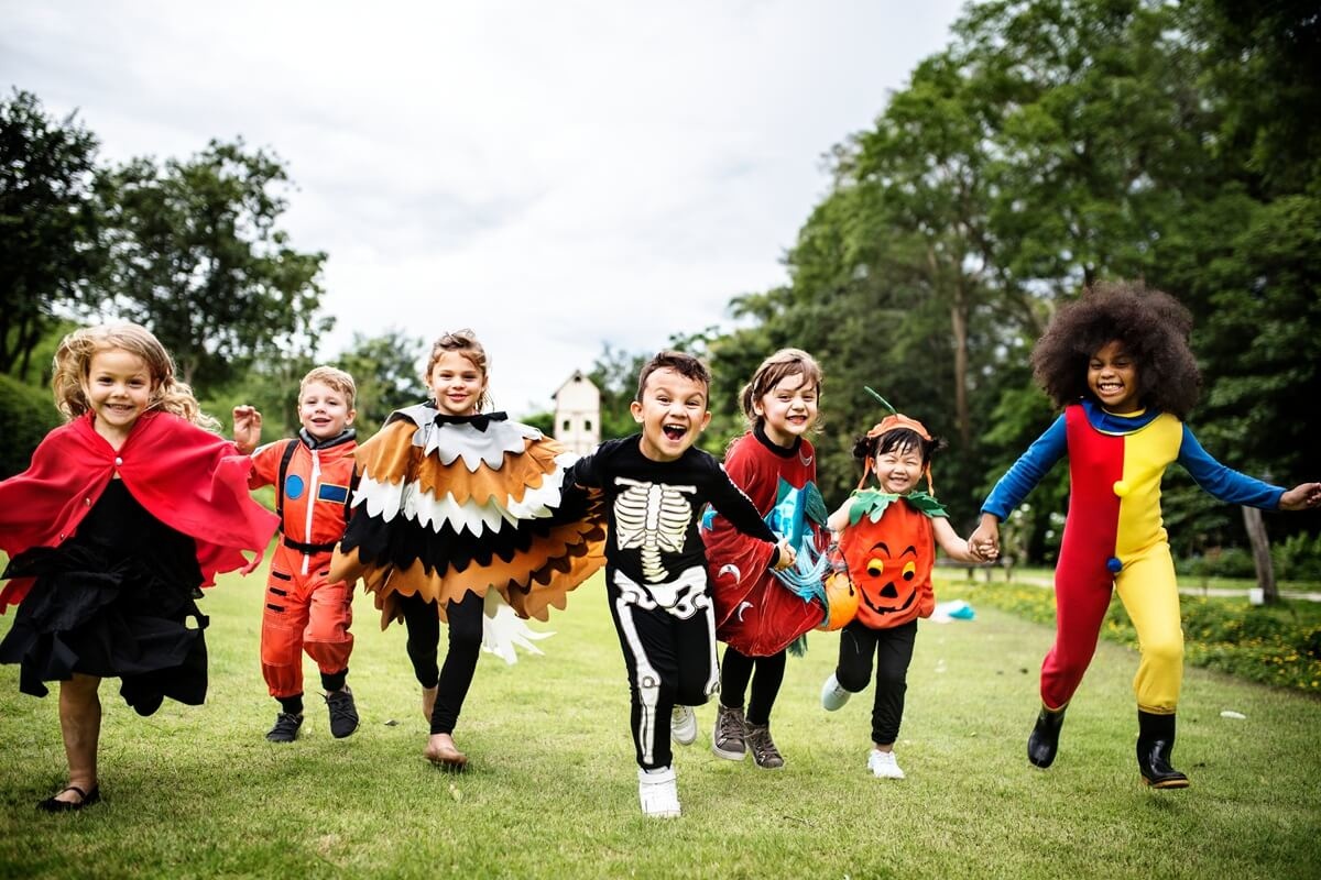 Gyerekek rohangálnak a kertben halloweeni jelmezekben
