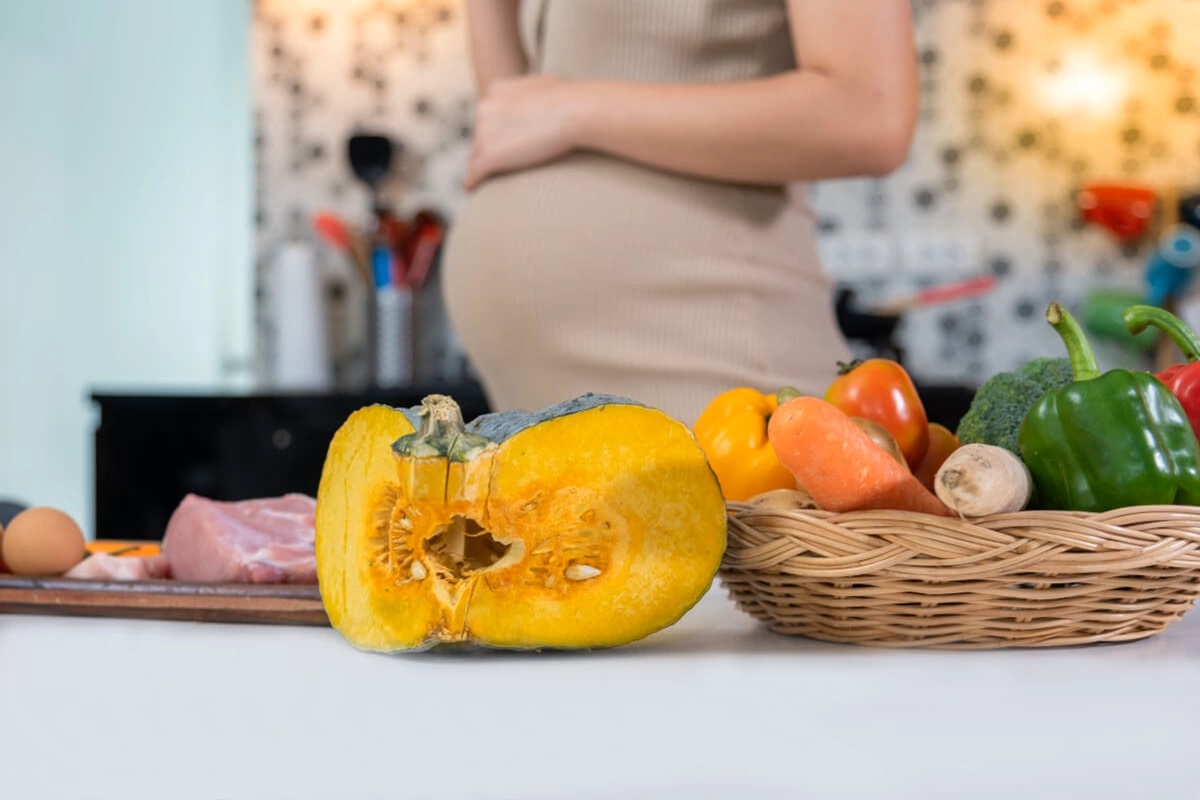 Těhotná žena zpracovávající dýni při vaření pokrmu