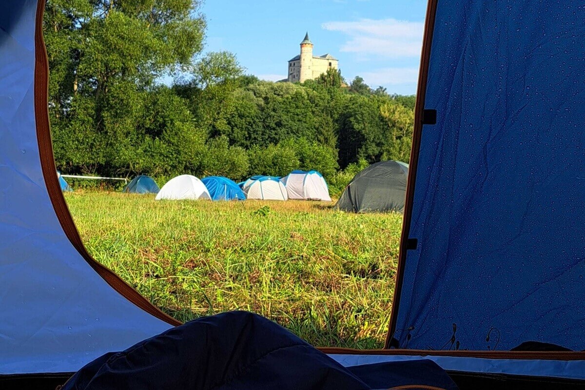 Reggeli kilátás a sátorból a napfényben úszó fellegvárra és a lenti sátortáborra.
