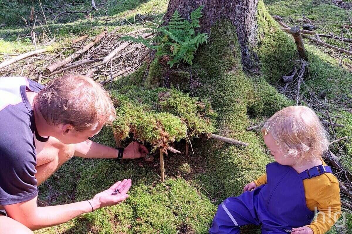 Rodina stavící lesní domeček z mechu a větví
