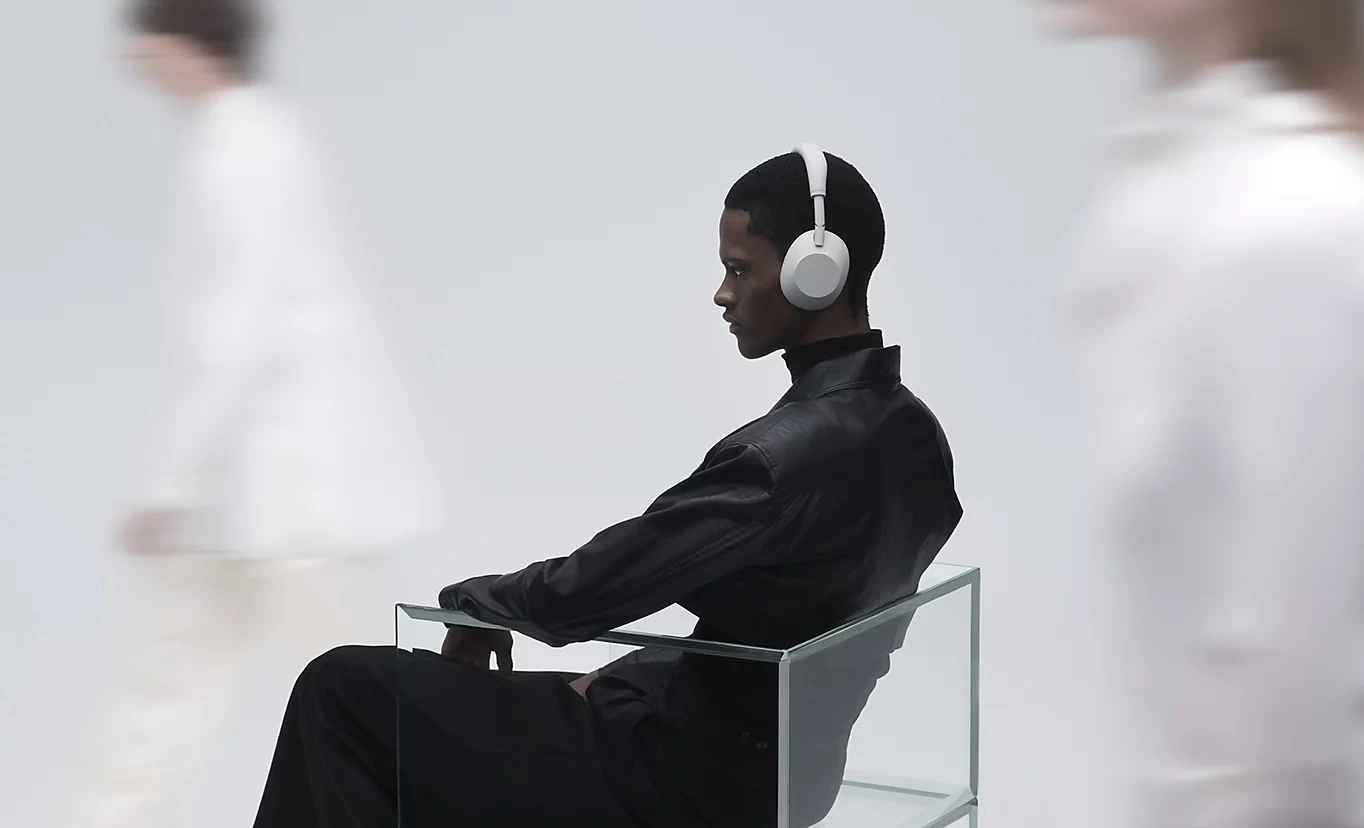 Sedící muž s nasazenými sluchátky Sony WH-1000XM6