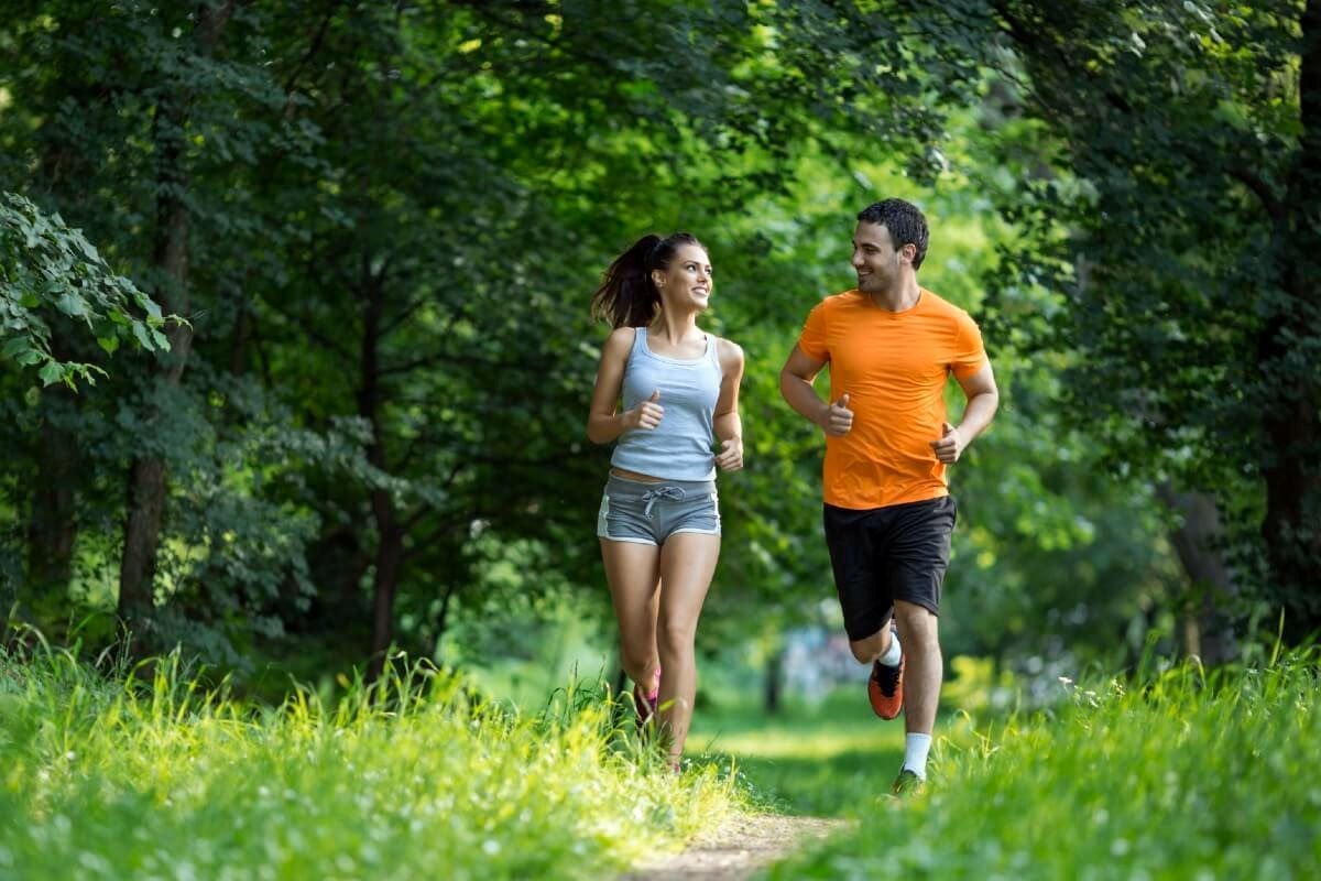 Cuplu făcând jogging în parc, promovând un stil de viață activ esențial pentru stimularea detoxifierii naturale a organismului