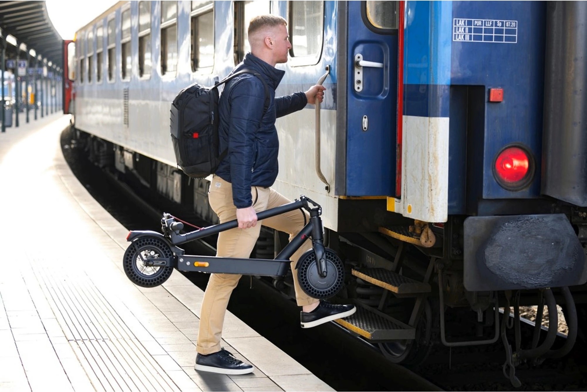 Koloběžka Sencor SCOOTER TWO je lehká. Snadno ji složíte a přenesete. Muž nastupuje do vlaku s koloběžkou Sencor SCOOTER TWO