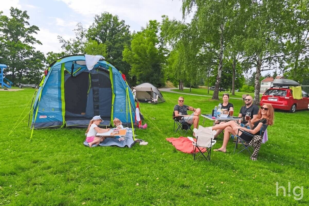 Rodinný stan Coleman Castle Pines 4 a kempaři relaxující na skládacích židlích