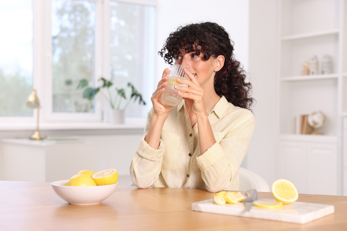 Žena, která pije vodu s citronem kvůli detoxu.