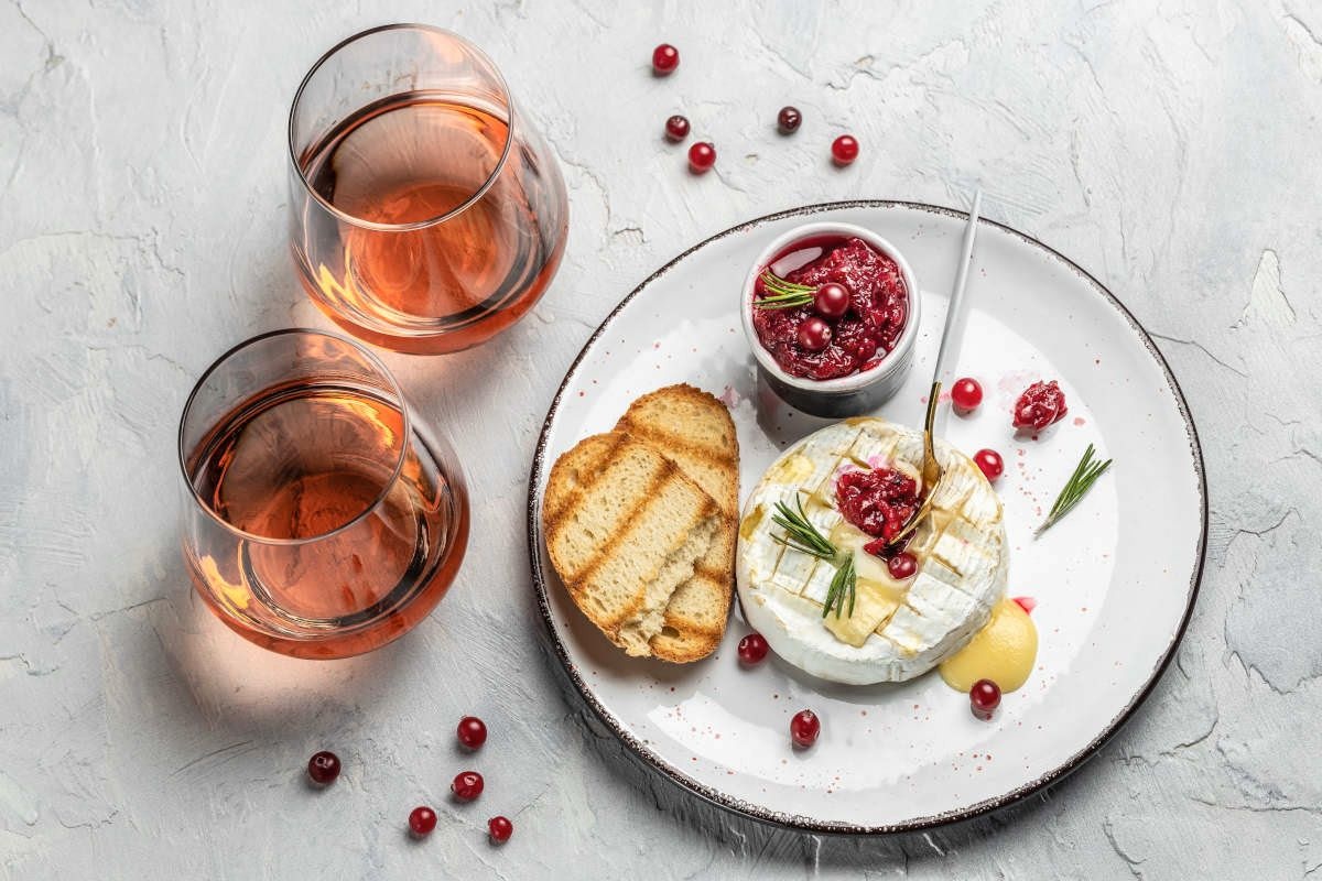 Brânză Camembert caldă, la grătar, cu sos de merișoare, pâine prăjită și două pahare de vin rosé
