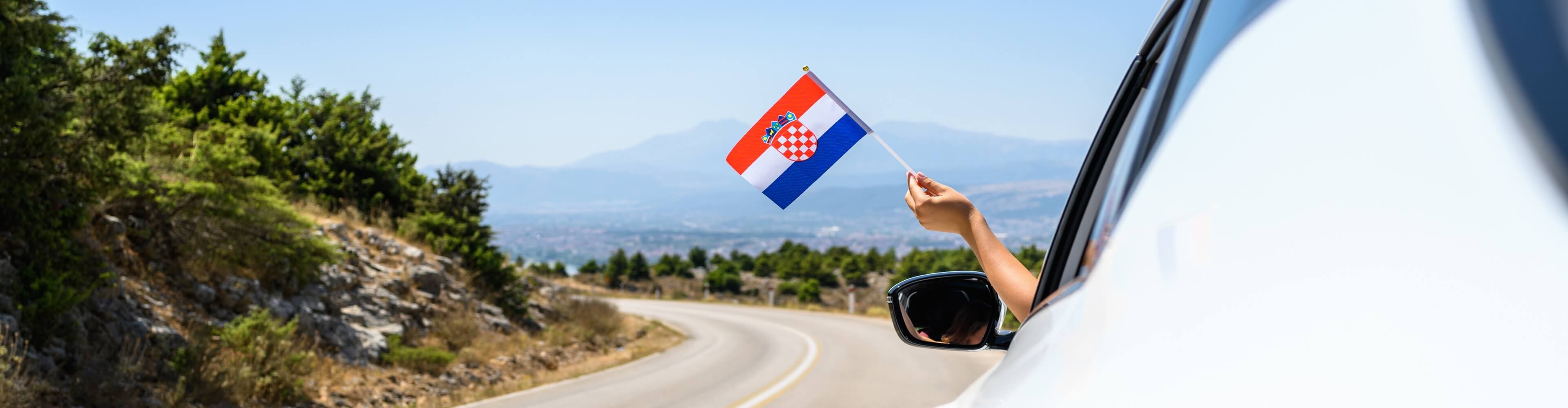 Natěšený řidič mává vlajkou cestou do Chorvatska