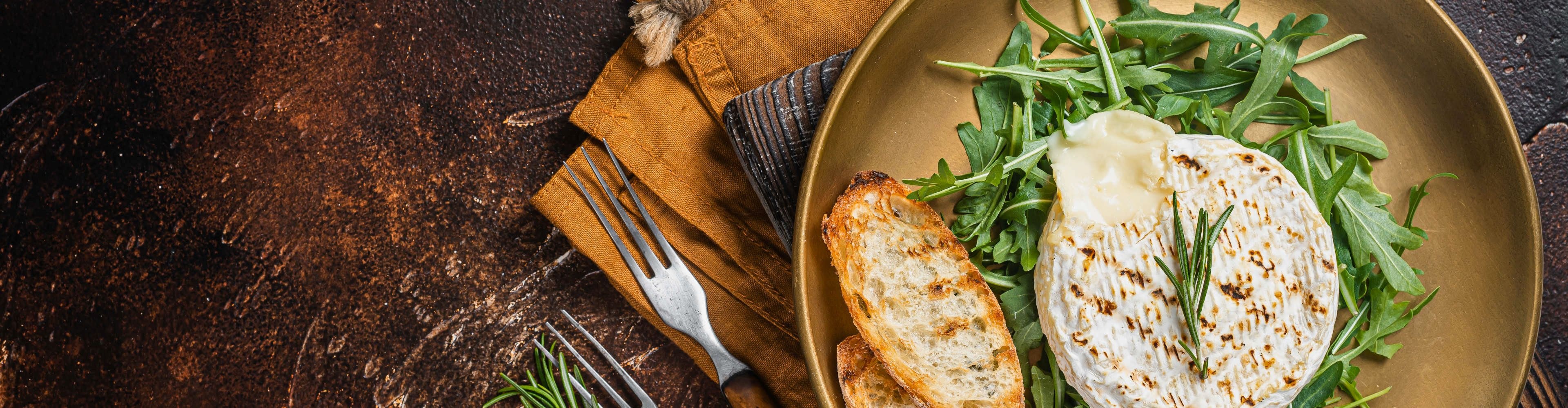 Brânză Camembert la grătar, caldă și topită, servită cu pâine prăjită și salată de rucola