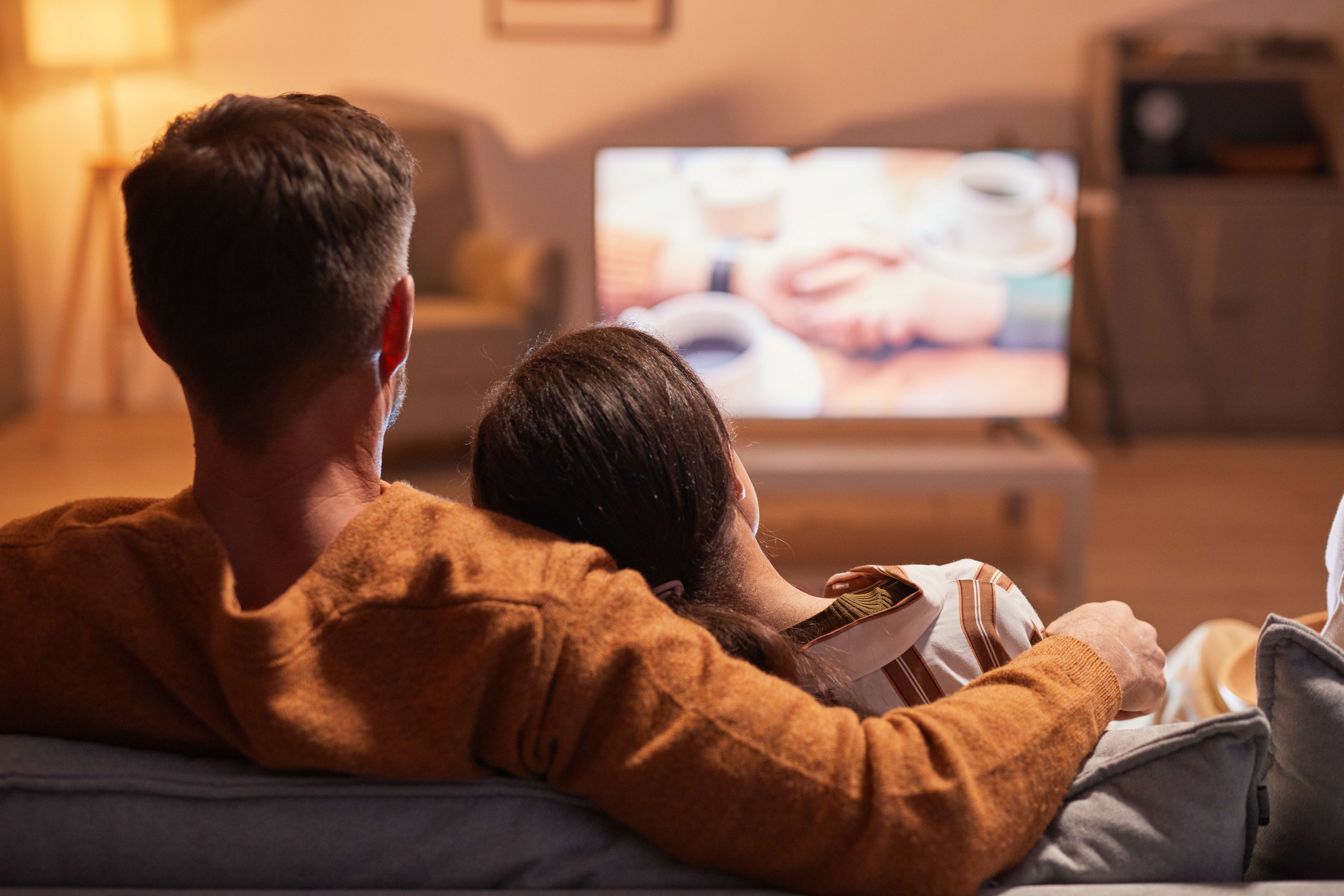 Fiatal pár tévét néz otthon a nappaliban