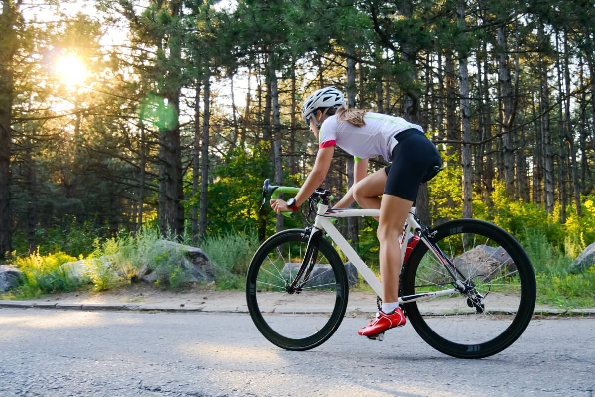Ciclistă pedalând în viteză vara Cum să te îmbraci pentru ciclism primăvara, vara și iarna