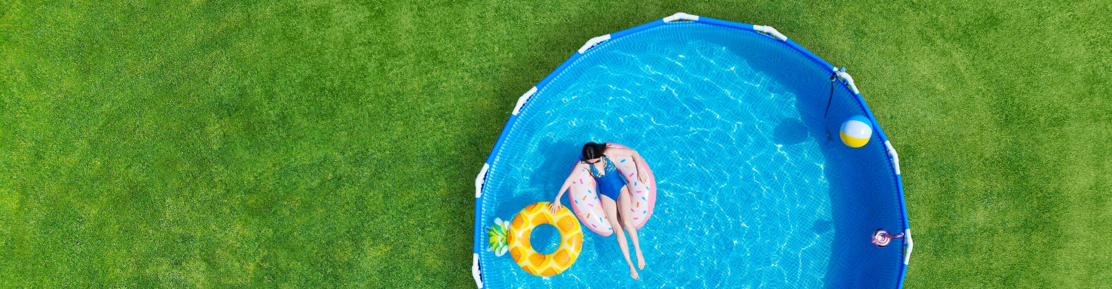 Piscine supraterane pentru curte: o femeie plutește pe un colac gonflabil într-o piscină rotundă, instalată pe gazonul din grădină